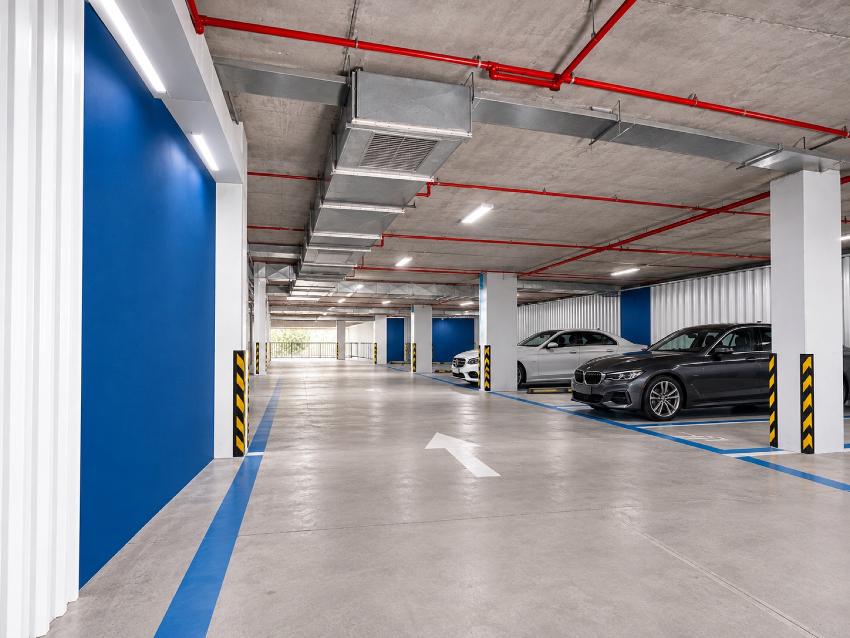 Proposed parking entrance with exposed concrete, red fire pipes and a blue accent wall